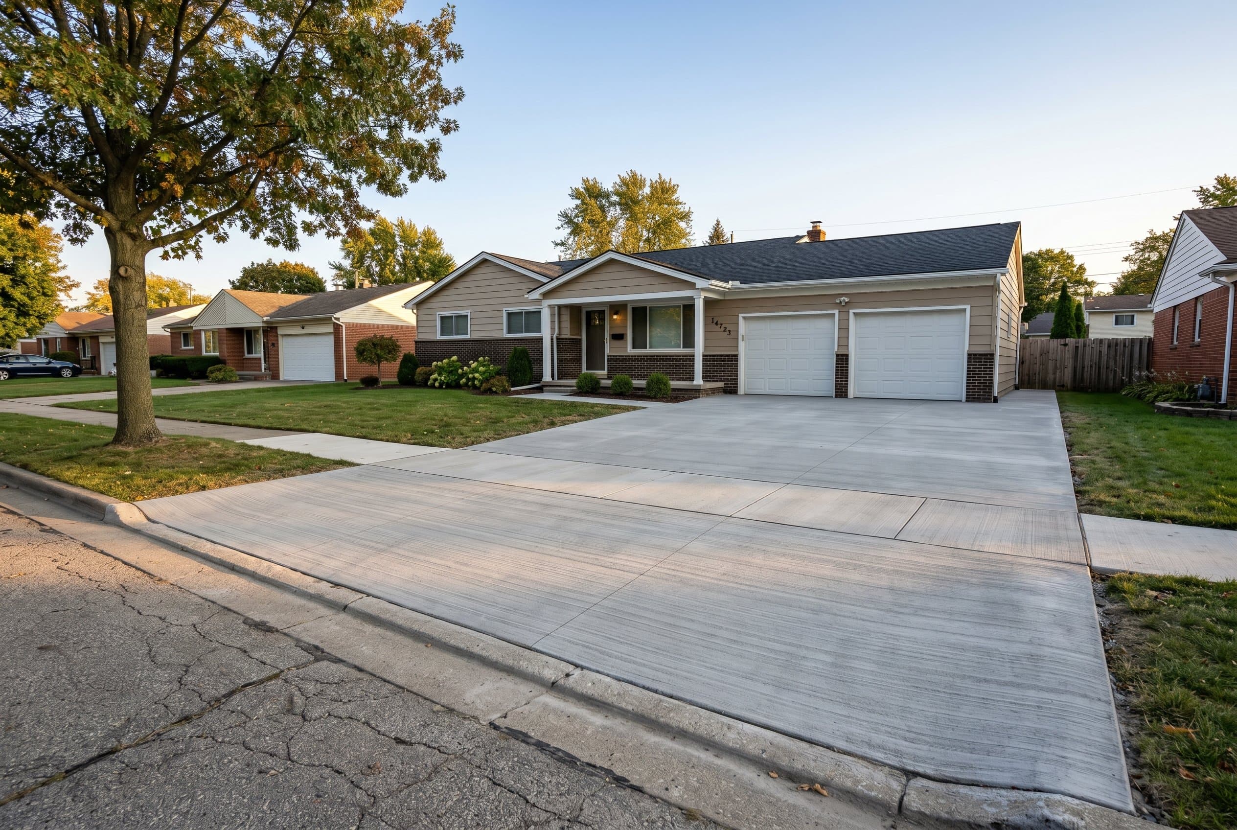Wide finished replacement driveway with curing compound applied.
